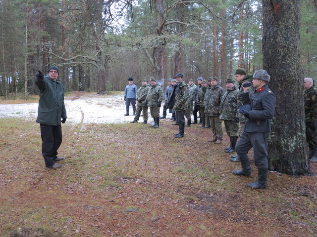 Museo Militarian museomestari Ilkka Vahtokari opettaa tuliasemien mittausta. Harjoitusjoukon johtaja Tuomo Ahonen vänrikin arvomerkeissä oikealla.
